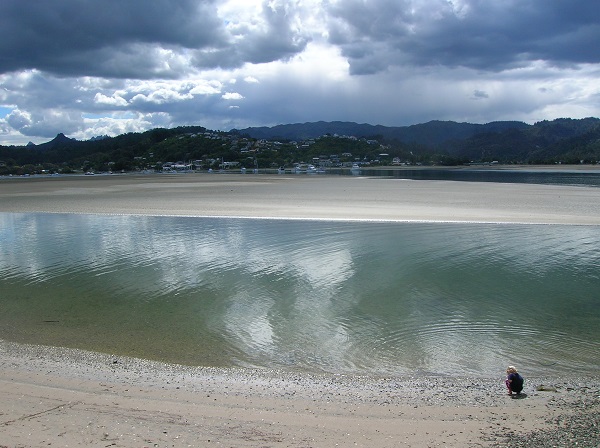 A boy plays on the shore of a wide river in Pauonui, New Zealand.